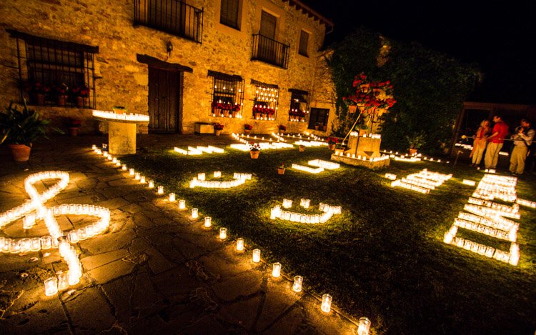 Casa de piedra por la noche, con un jardin iluminado con velas