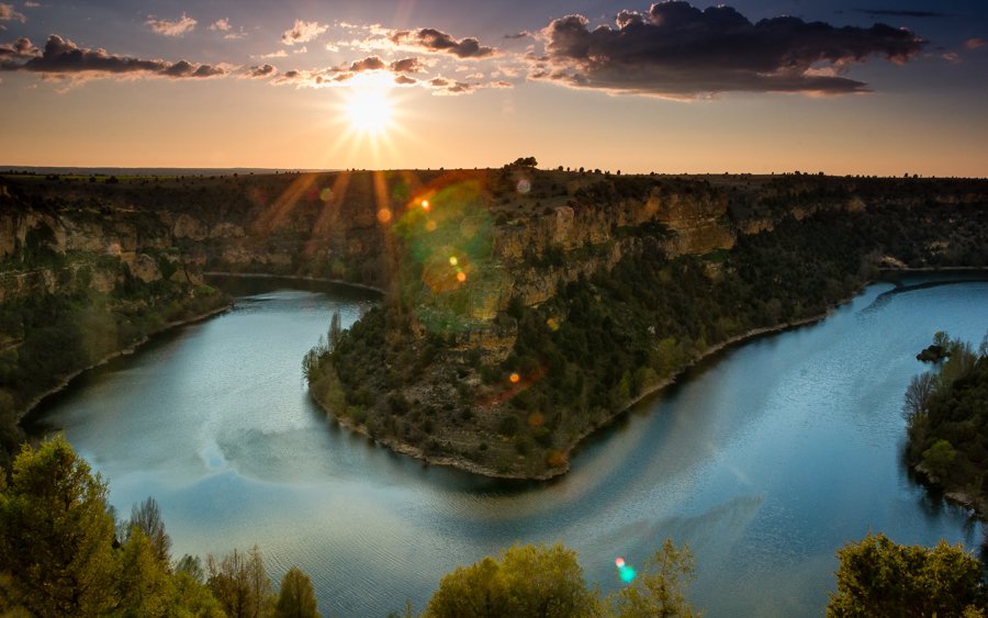 Sunset in Hoces del Duraton, a river with reflections in the water and a clift with vegetation