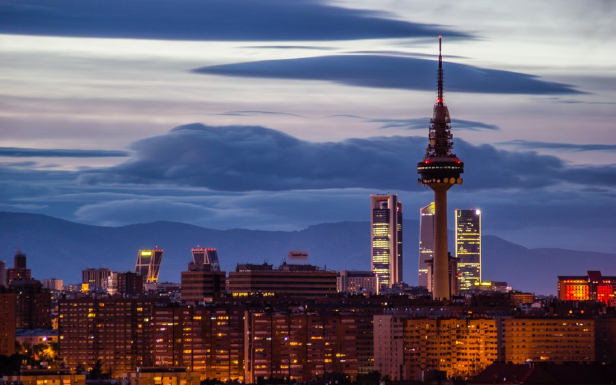 City lights during the night in Madrid, with a cloudy sky and the skyscrapers 