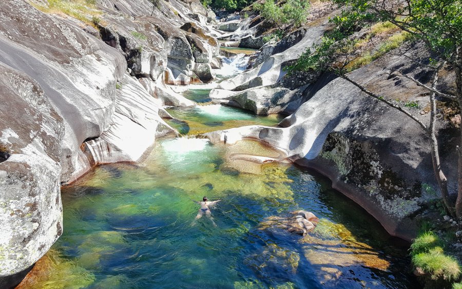 Pools in Garganta de los Infiernos, a river with clean water and people swimming.